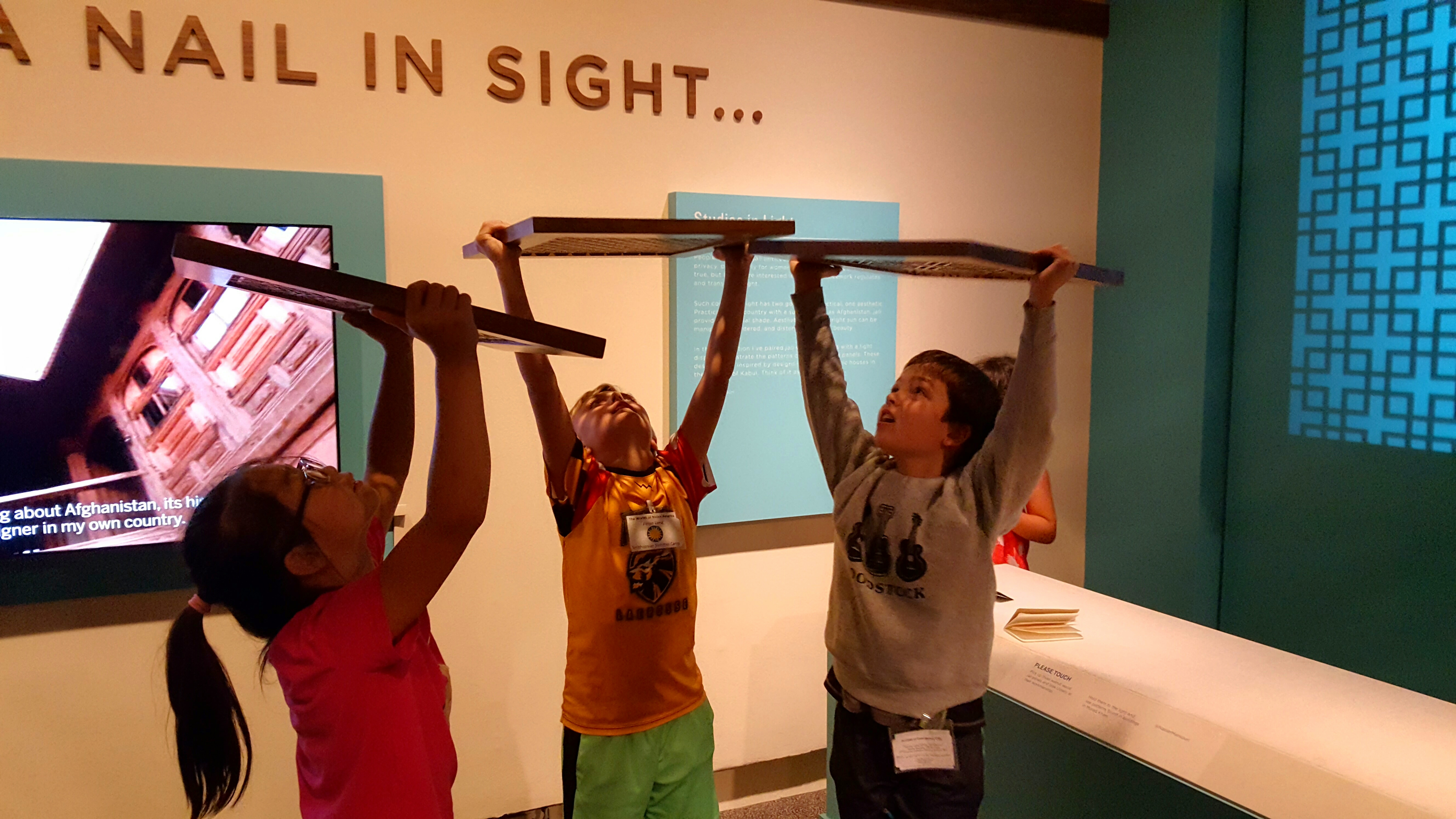 Children looking up at the ceiling through exhibit interactives inside a museum.